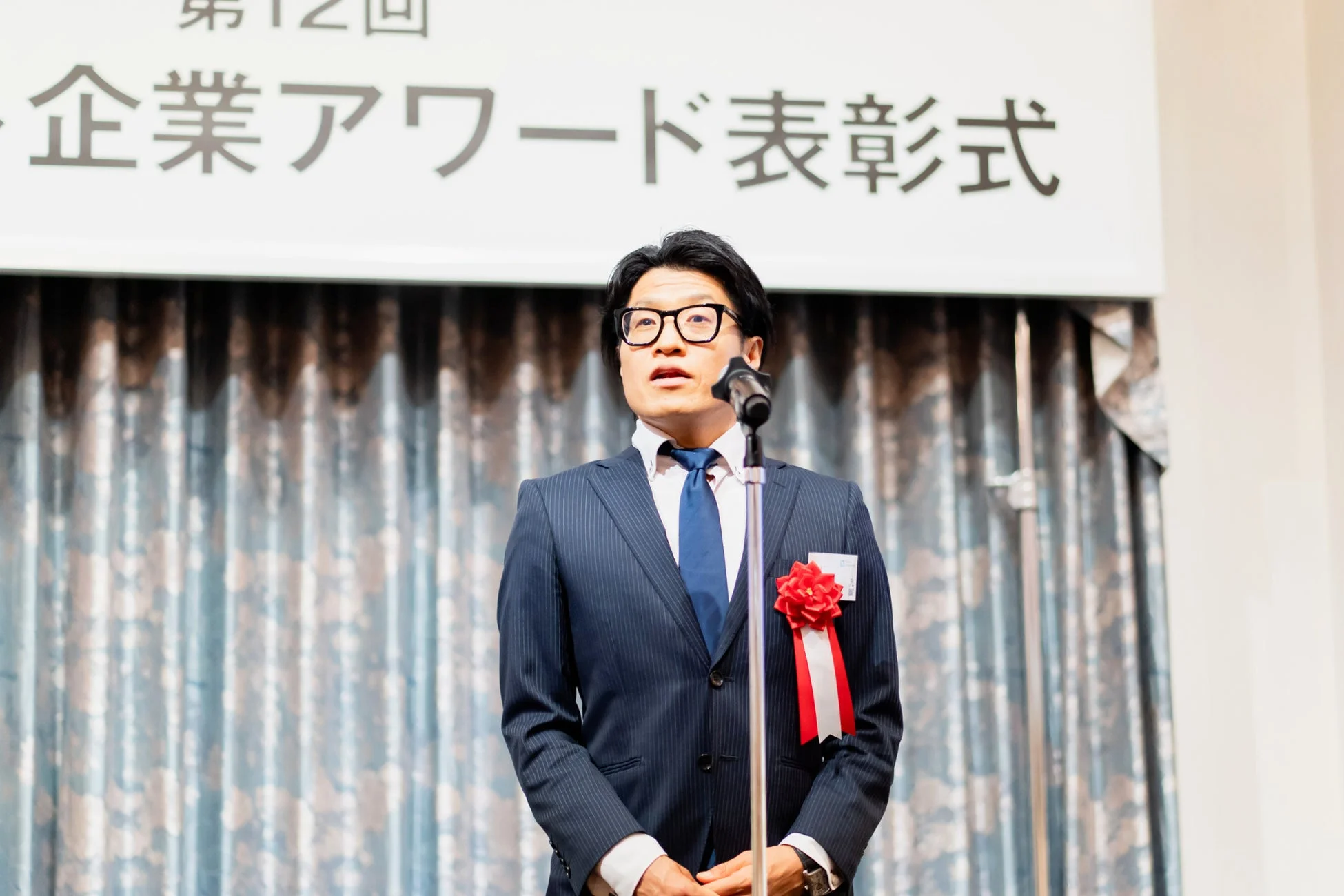 企業アワード表彰式でスピーチする男性