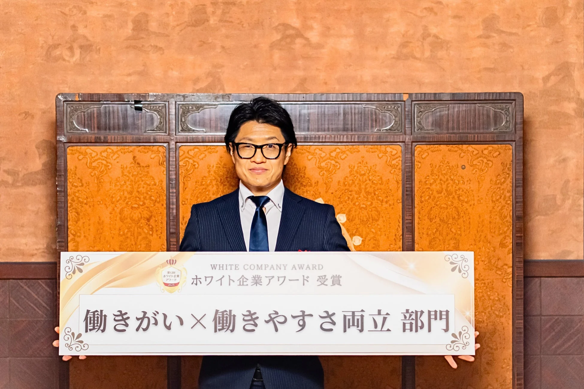 ホワイト企業アワード働きがい×働きやすさ両立部門賞のバナーを掲げる男性