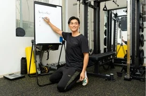 ジムでホワイトボードを指しながら説明する男性