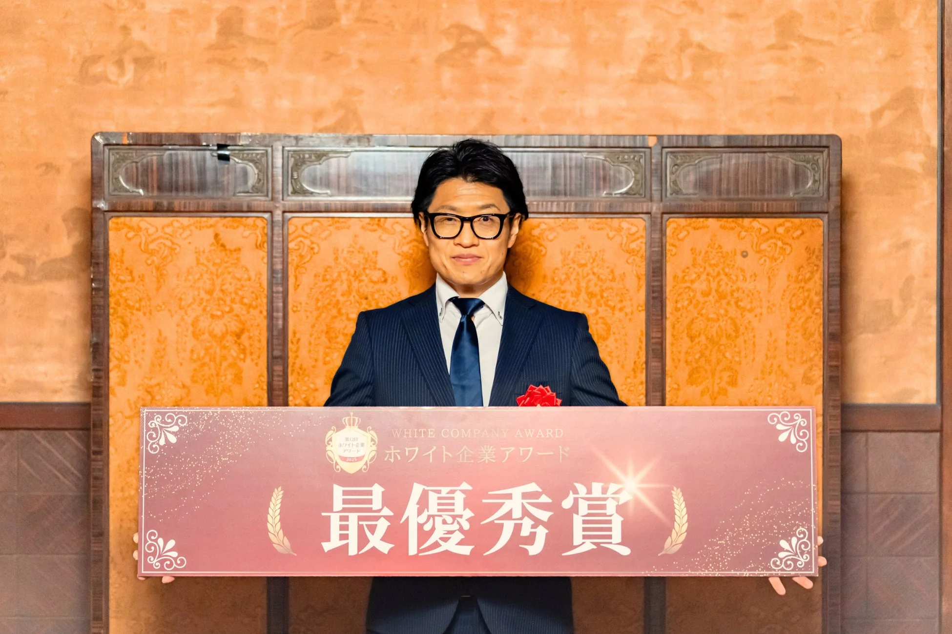 ホワイト企業アワード最優秀賞のバナーを掲げる男性