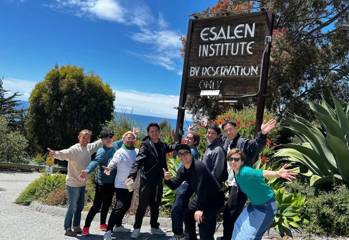 エサレン研究所の看板の前でポーズをとる男性グループ