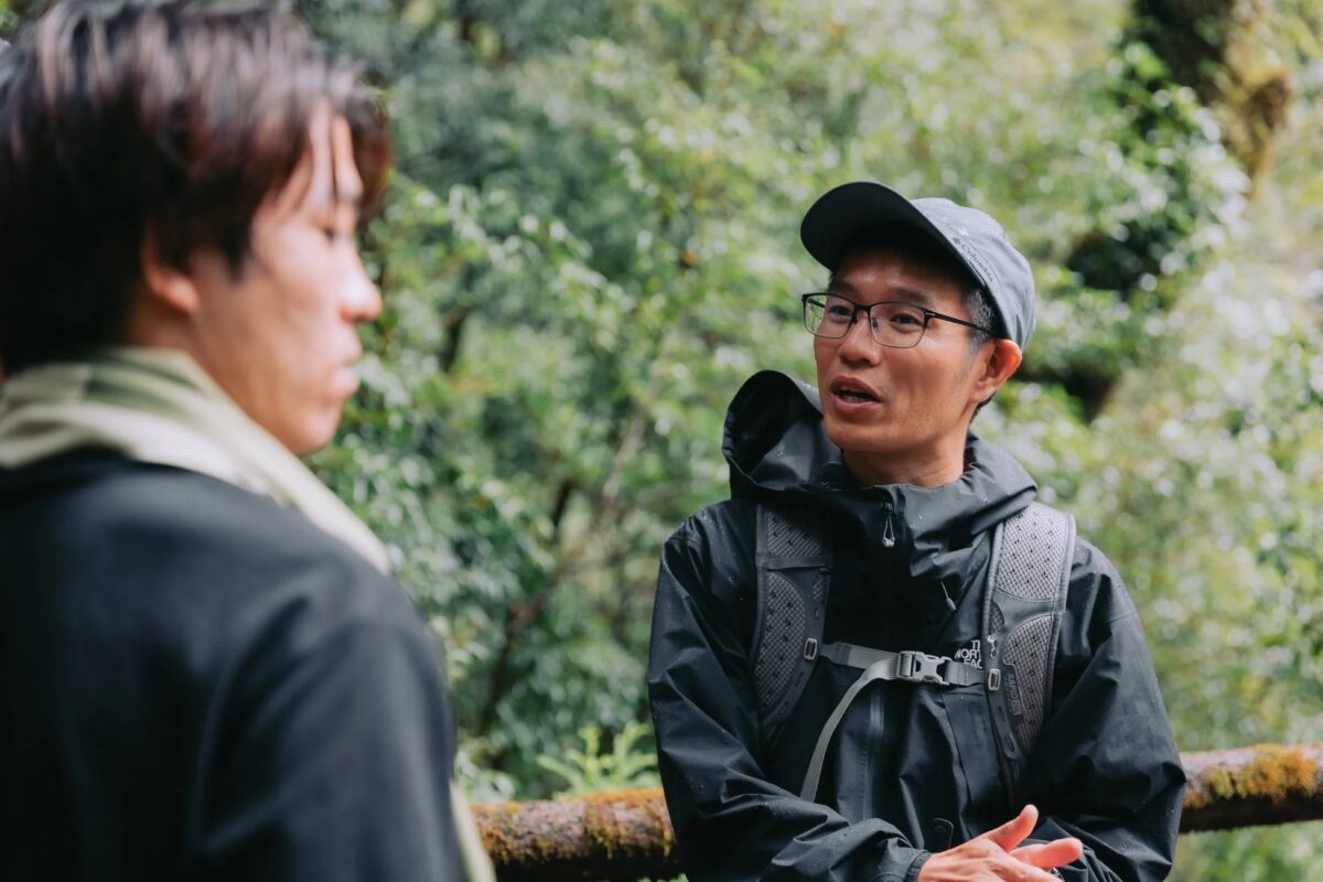 森の中で二人の男性が会話している様子