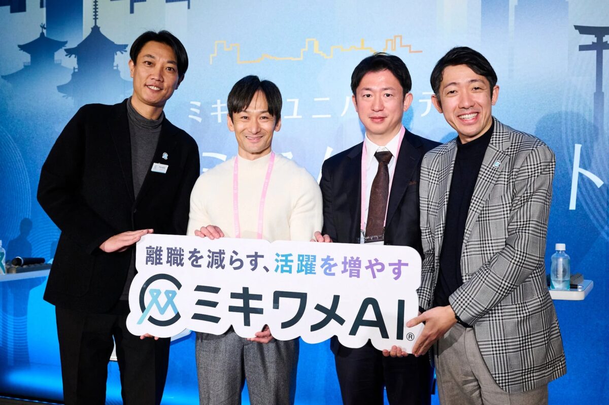ビジネスイベントで、4人の男性が「離職を減らす、活躍を増やす ミキワメAI」と書かれた看板を持って笑顔でポーズをとっています。