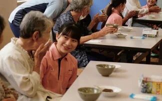 高齢者と若い女性が食事と交流を楽しむ様子