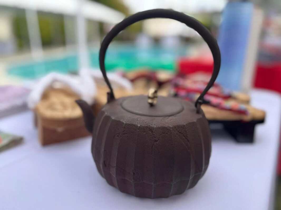 屋外のテーブルに置かれた、日本の伝統的な鉄瓶のクローズアップ画像です。