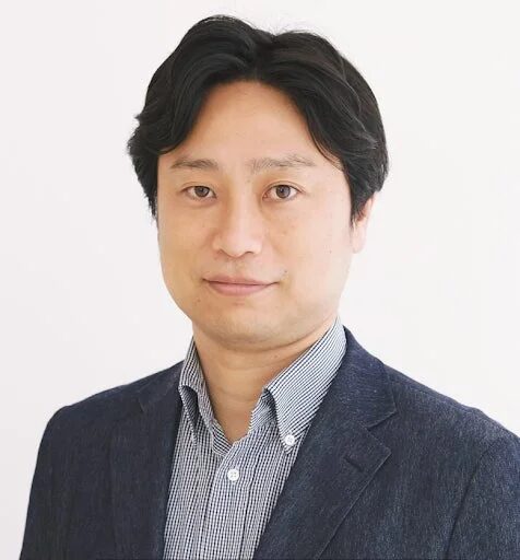 白い背景の前で、紺色のジャケットとストライプのシャツを着用したアジア人男性の顔写真です。男性はカメラをまっすぐ見つめており、ビジネスシーンに適した真面目でプロフェッショナルな印象を与えます。